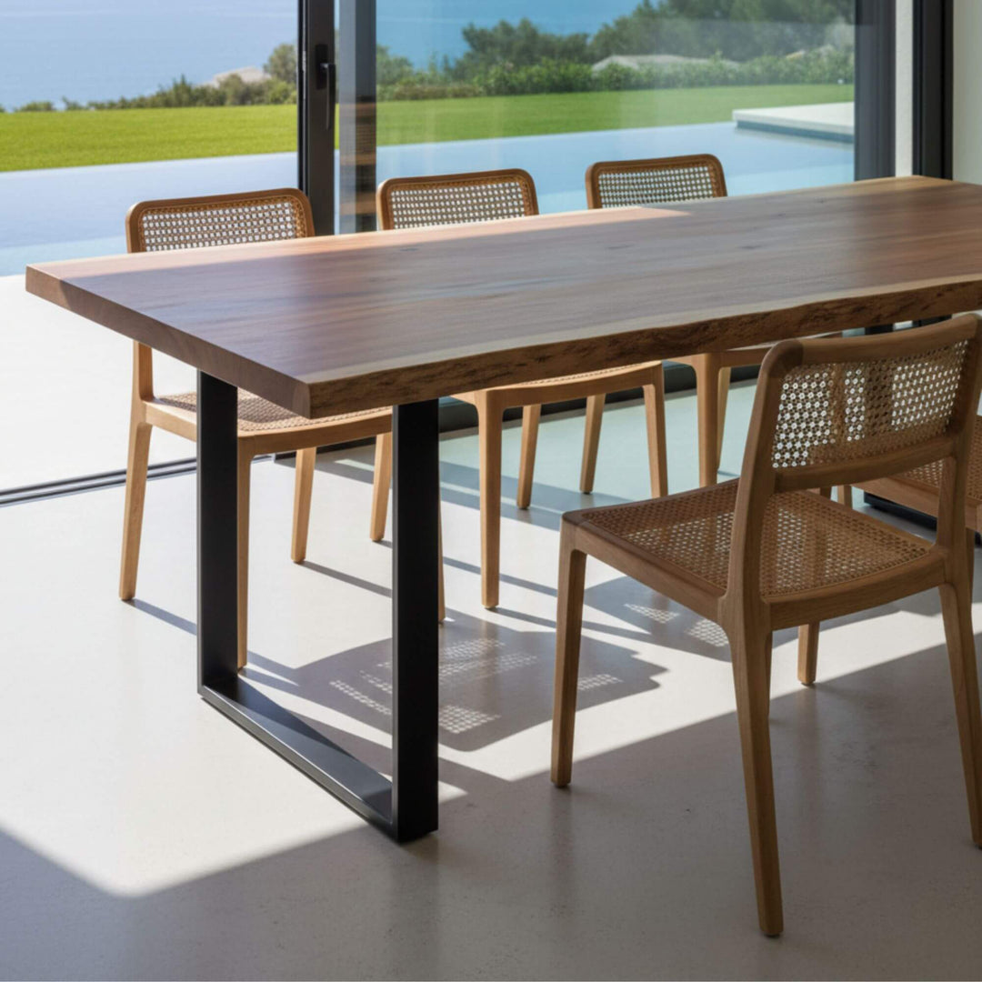 Side perspective of the Acacia Dining Table paired with wooden dining chairs.