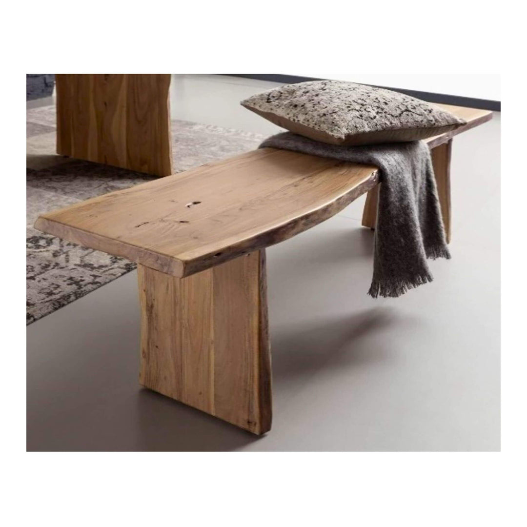 Solid acacia wood bench with live-edge design, showcasing natural wood grain and warm tones, styled with a cushion and throw in a modern interior.
