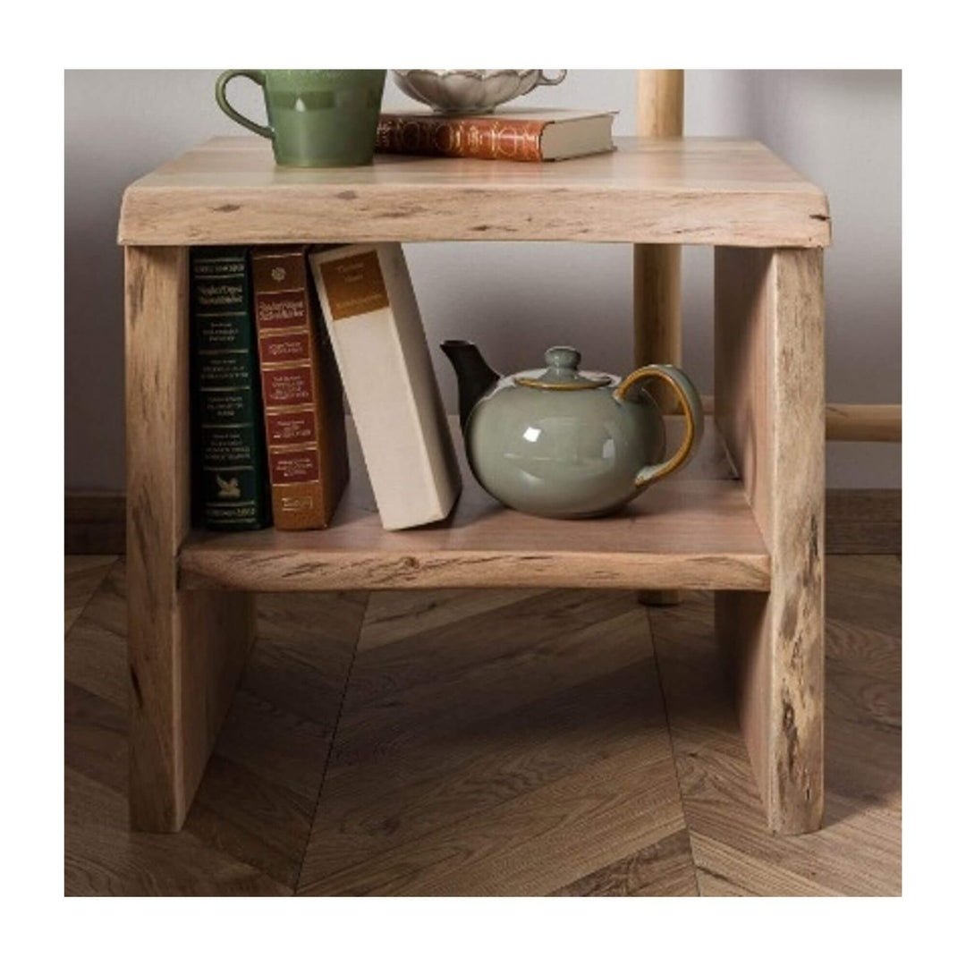 Solid acacia wood side table with live-edge design and lower shelf, styled with books and a ceramic teapot in a cozy interior setting.