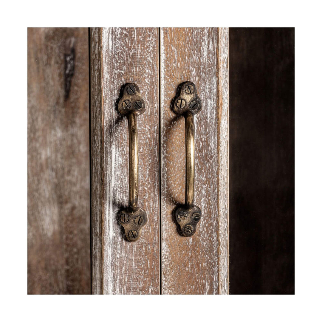Close-up of the vertical brass handles on the wardrobe doors, mounted on rustic white-washed mango wood.
