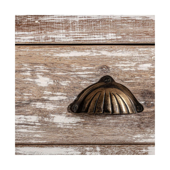 Detailed view of the brass cup handle on the Adrastea wardrobe drawer against the distressed white-washed mango wood.