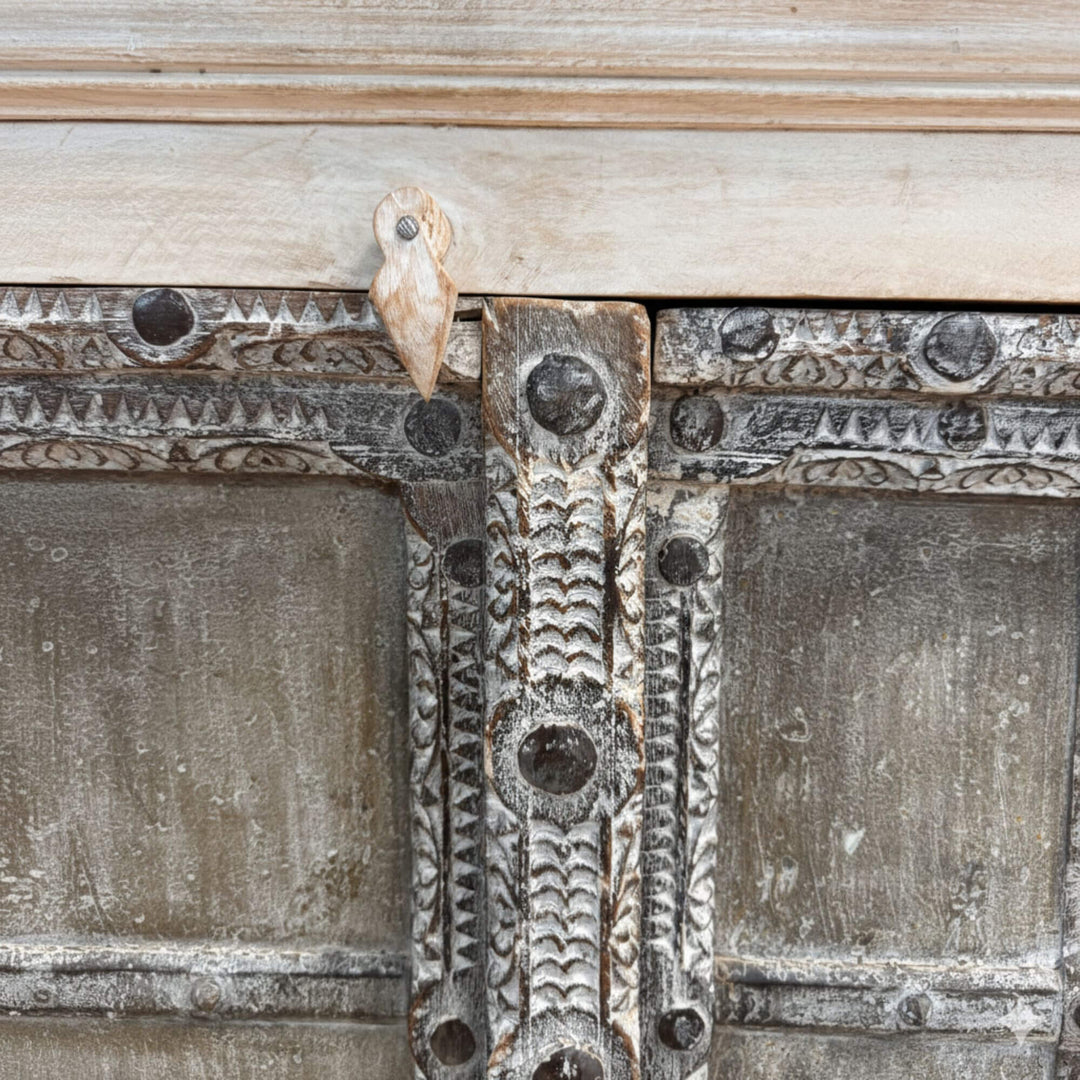 Close-up of the carved details and aged finish on the wardrobe doors.