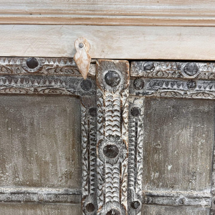 Close-up of the carved details and aged finish on the wardrobe doors.