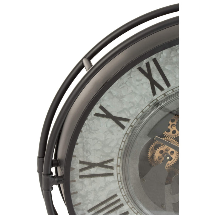Close-up of Aion Roman Clock showing metal frame, Roman numerals, and exposed bronze gears