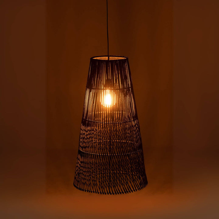 Alexia lamp glowing warmly in a dimly lit room, showing woven rattan texture.