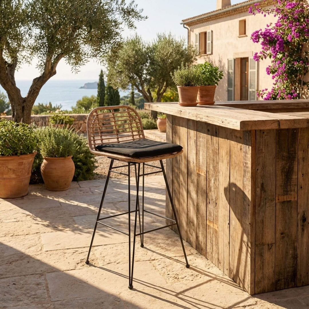 Wooden outdoor bar with a aMALAFI Bar Stool and potted plants in a scenic location.