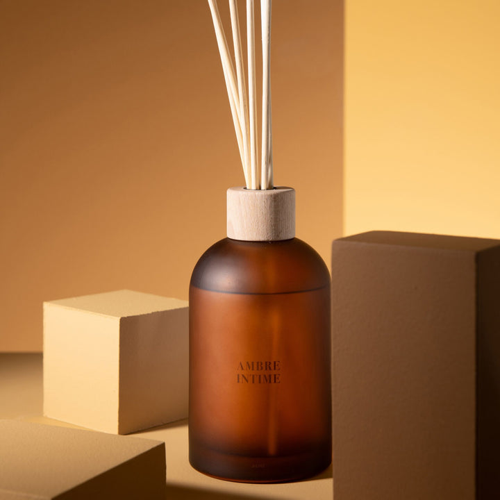 Lifestyle setting showing the Amber Intime Diffuser placed on a warm-toned surface.
