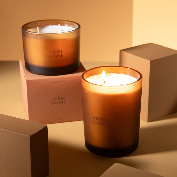 Lit Amber Intime candle creating a warm glow in a styled interior setting.