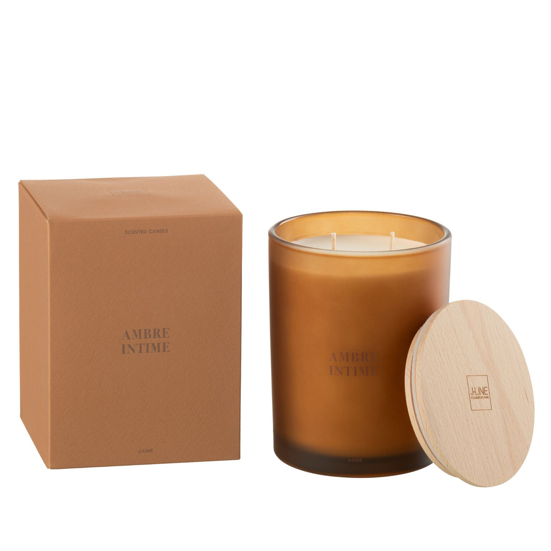 Amber Intime scented candle with amber glass jar and wooden lid next to its packaging.