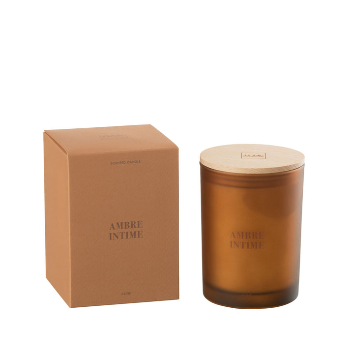 Amber Intime scented candle with amber glass jar and wooden lid next to its packaging.