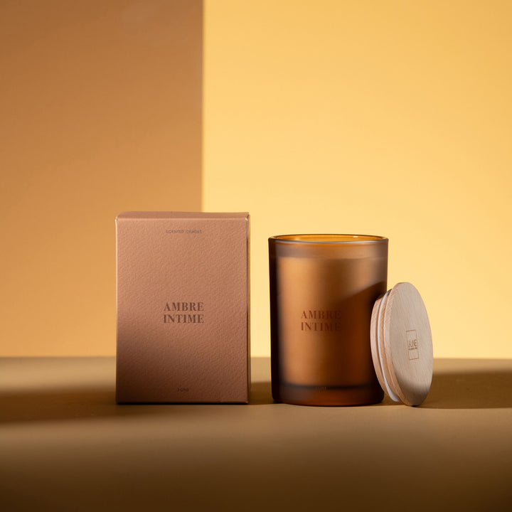 Medium-sized Amber Intime candle with lid leaning against the container.