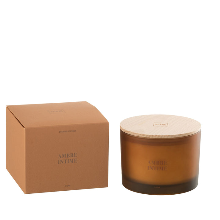 Amber Intime scented candle with amber glass jar and wooden lid next to its packaging.