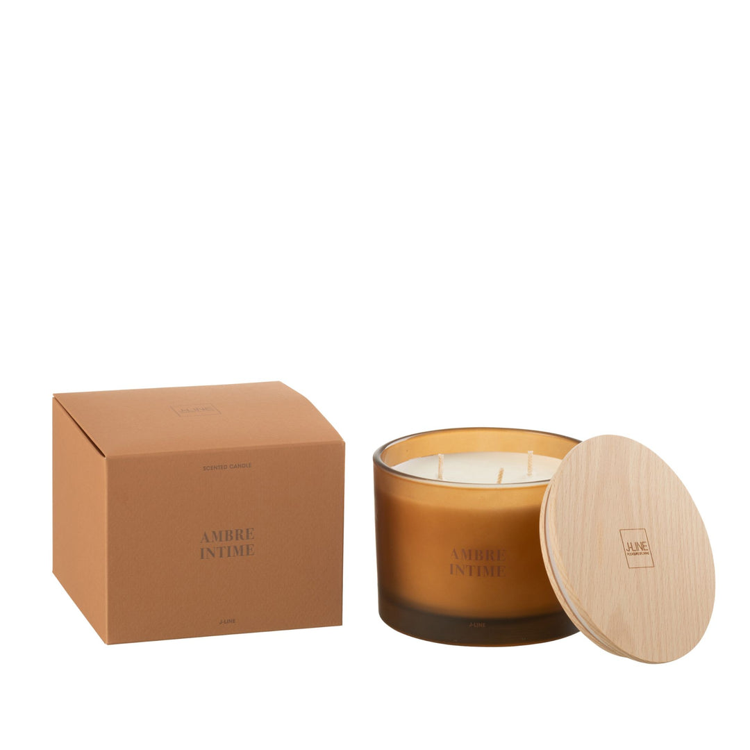 Amber Intime scented candle with amber glass jar and wooden lid next to its packaging.