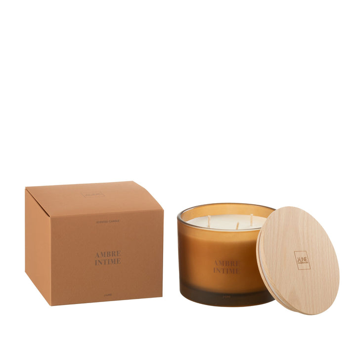 Amber Intime scented candle with amber glass jar and wooden lid next to its packaging.