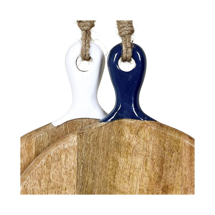 Close-up of two Anaya round mango wood chopping boards with ceramic handles in white and navy.