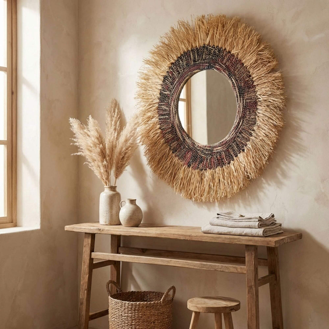 Woven Angkasa mirror with natural elements on a wooden console table in a warm-toned room.