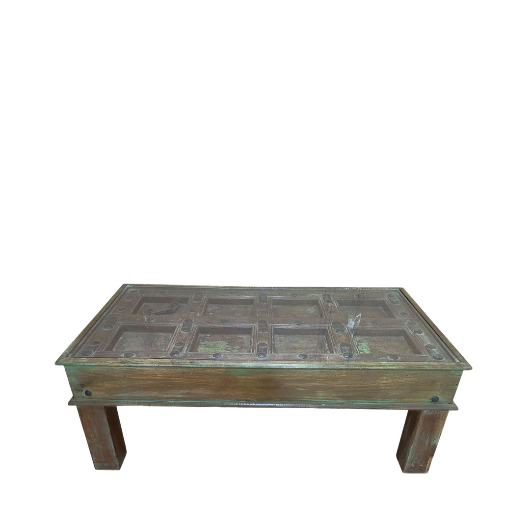 Front view of the antique door coffee table showcasing its carved tabletop and solid wood legs.