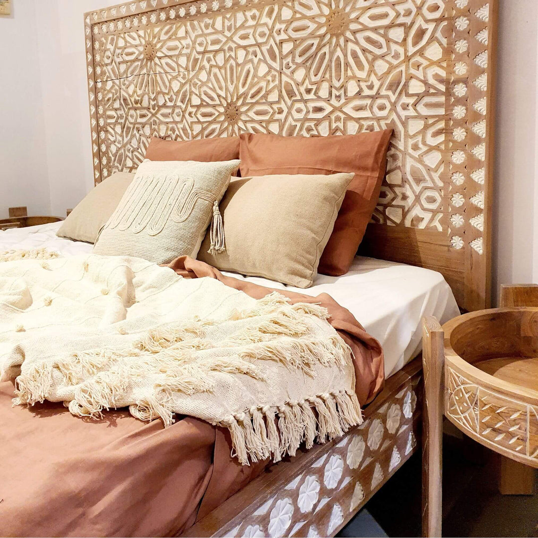 Aphrodite side table styled beside a teak bed with neutral bedding