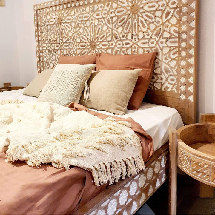 Aphrodite side table styled beside a teak bed with neutral bedding