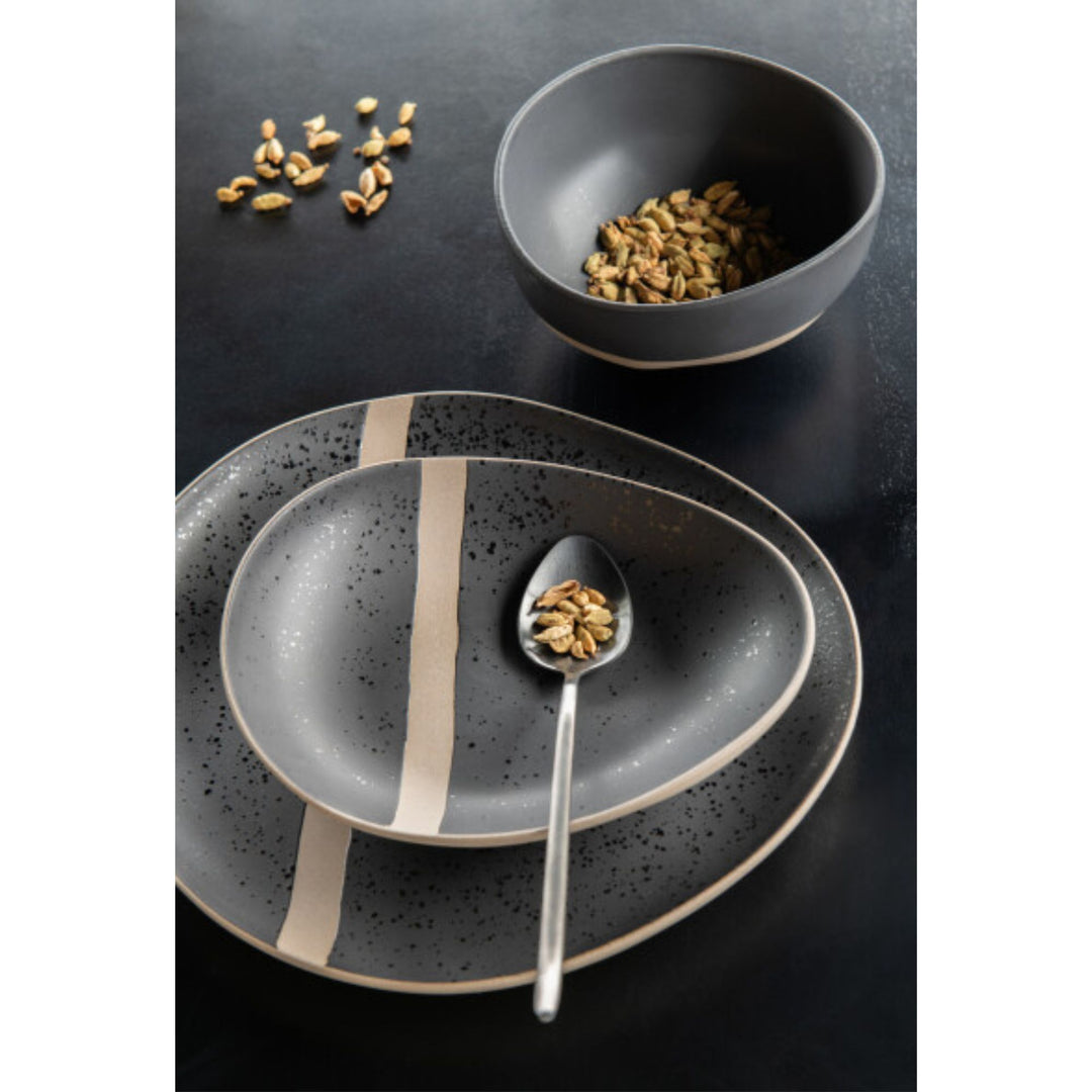 Arcai tableware collection styled on a black dining table with plates and bowls