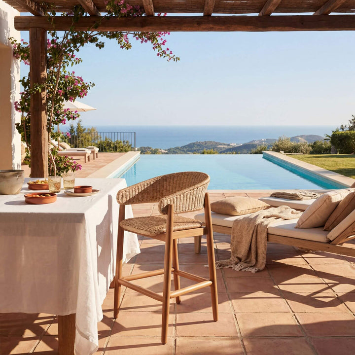 Styled outdoor bar setting featuring the Arena bar stool on a terrace with sea view.