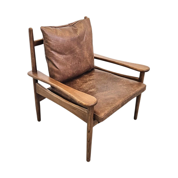 Angled view of Asikni teak wood chair with leather cushions