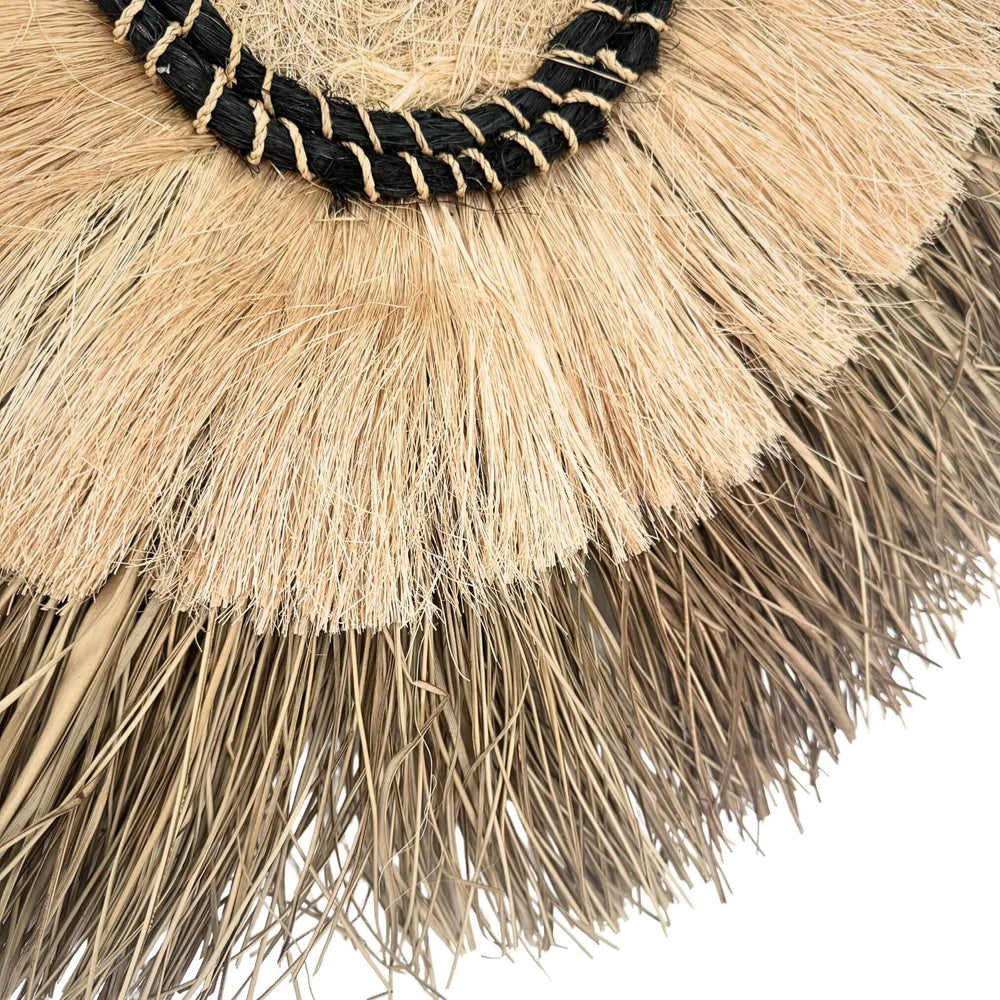 Close-up of Amara Wall Deco showing natural fiber fringe and woven black detailing.