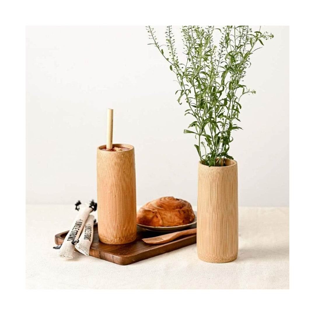 Bamboo cup used as drink tumbler and another as vase with herbs on a breakfast table.