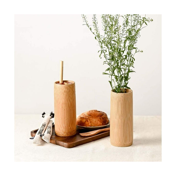 Bamboo cup used as drink tumbler and another as vase with herbs on a breakfast table.