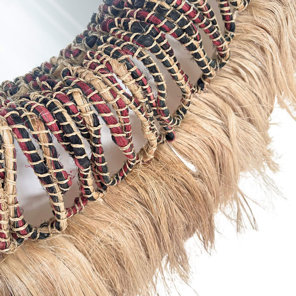 Close-up of Banyu Mirror with braided design and tassels on a white background