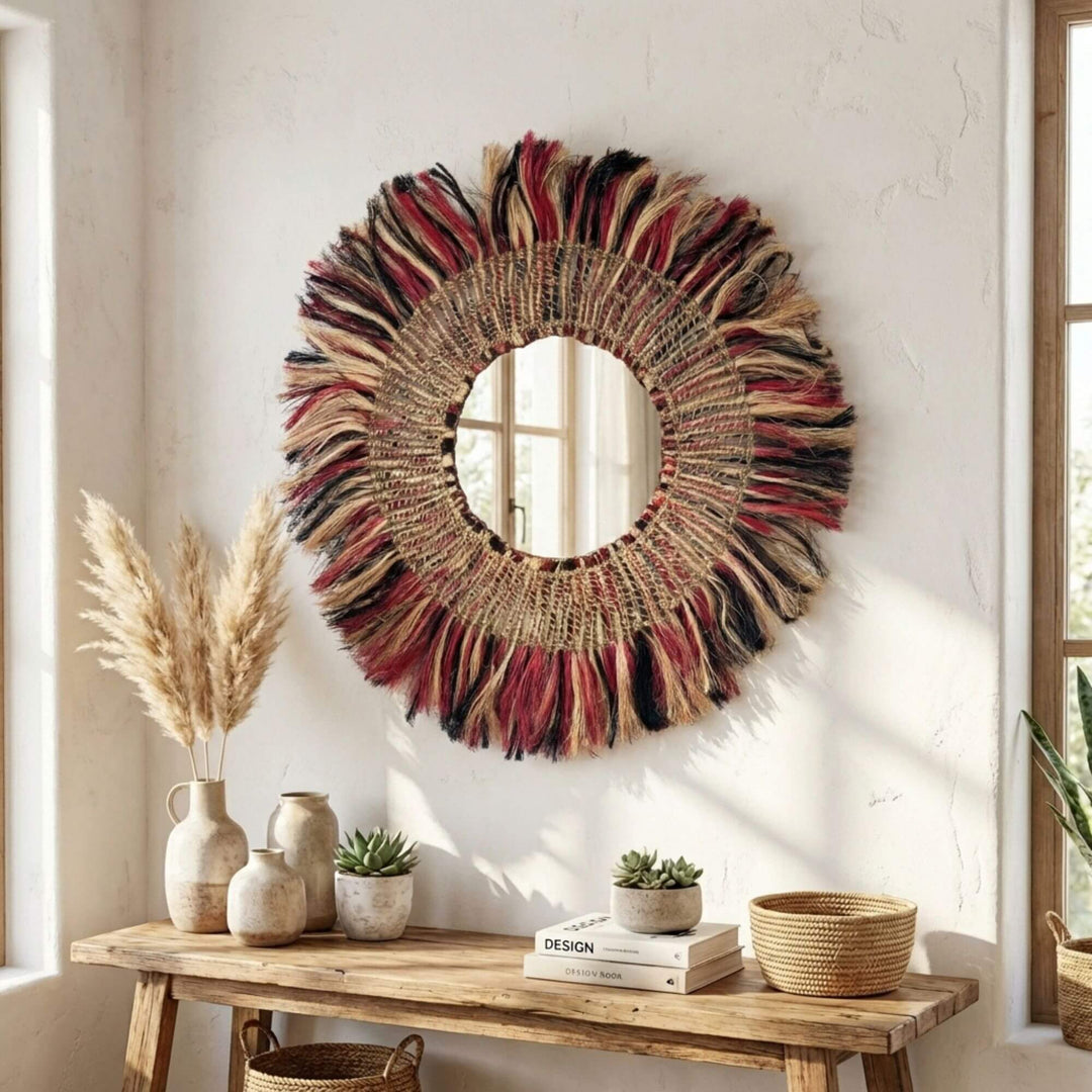 Decorative Bayu mirror with colorful fringes on a wall above a wooden console table.