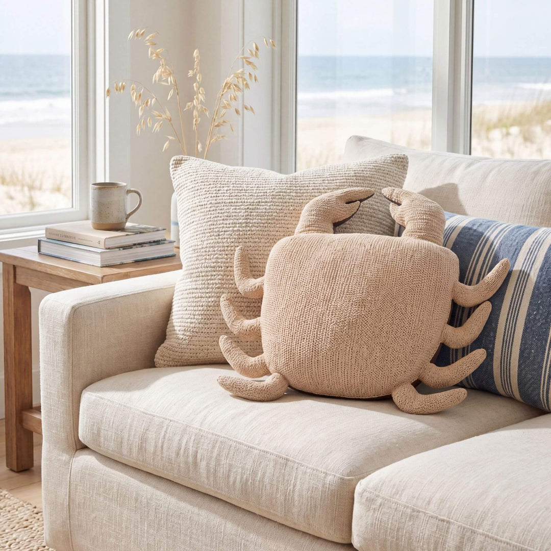 Styled coastal interior setting featuring the Beach Crab cushion on a sofa with soft neutral textiles.