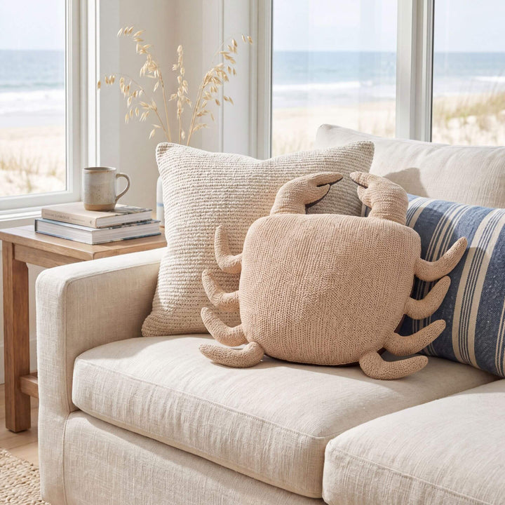 Styled coastal interior setting featuring the Beach Crab cushion on a sofa with soft neutral textiles.