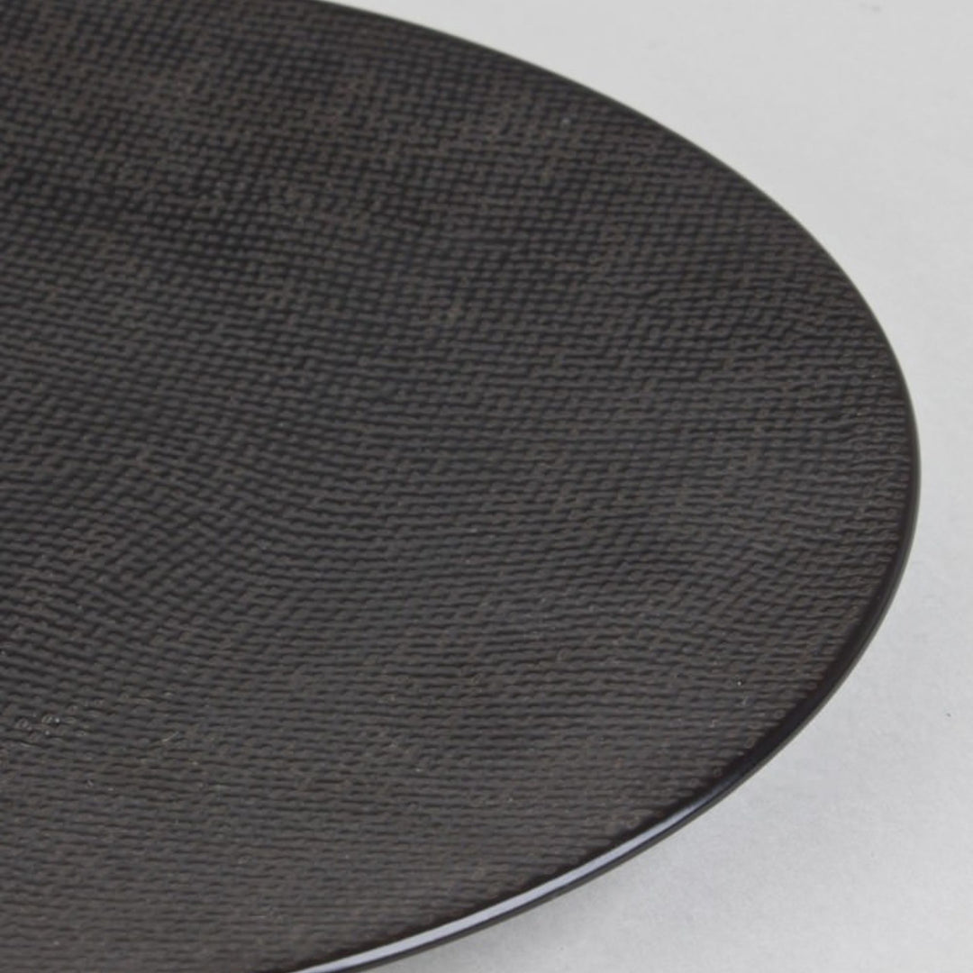 Close up view of black ceramic plate with subtle textured surface.