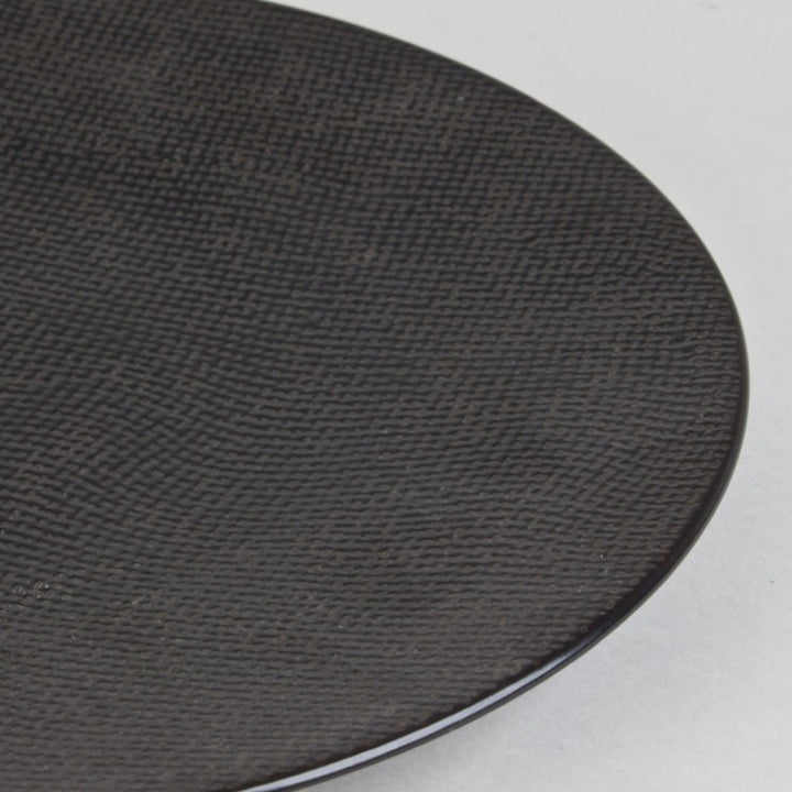 Close up view of black ceramic plate with subtle textured surface.