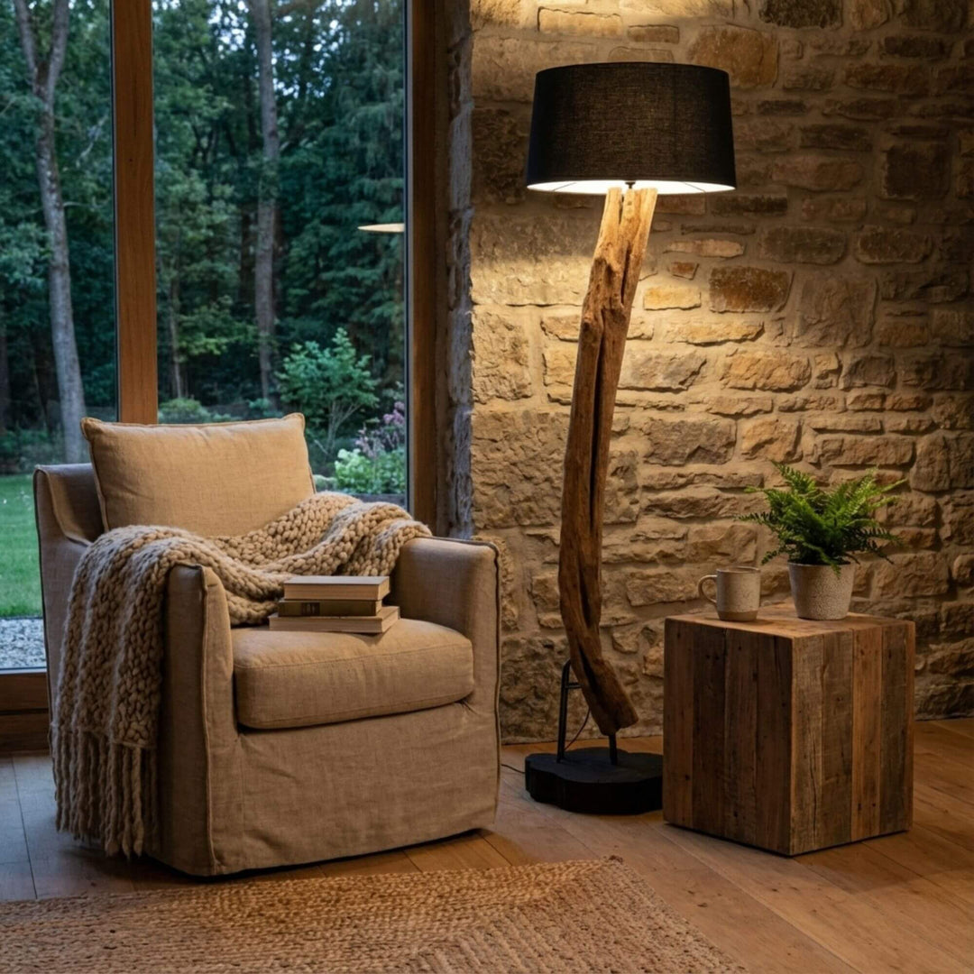 Styled interior view of Boatu Floor Lamp placed next to an armchair, highlighting its warm ambient lighting and natural wood form.
