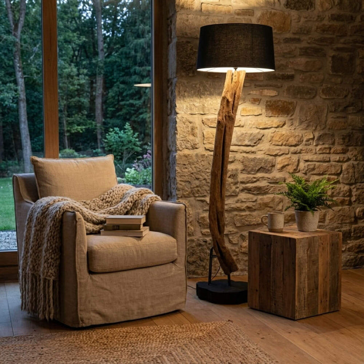 Styled interior view of Boatu Floor Lamp placed next to an armchair, highlighting its warm ambient lighting and natural wood form.