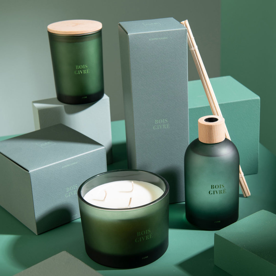 Lifestyle setup featuring the Bois Givré candle collection arranged on green-toned blocks.