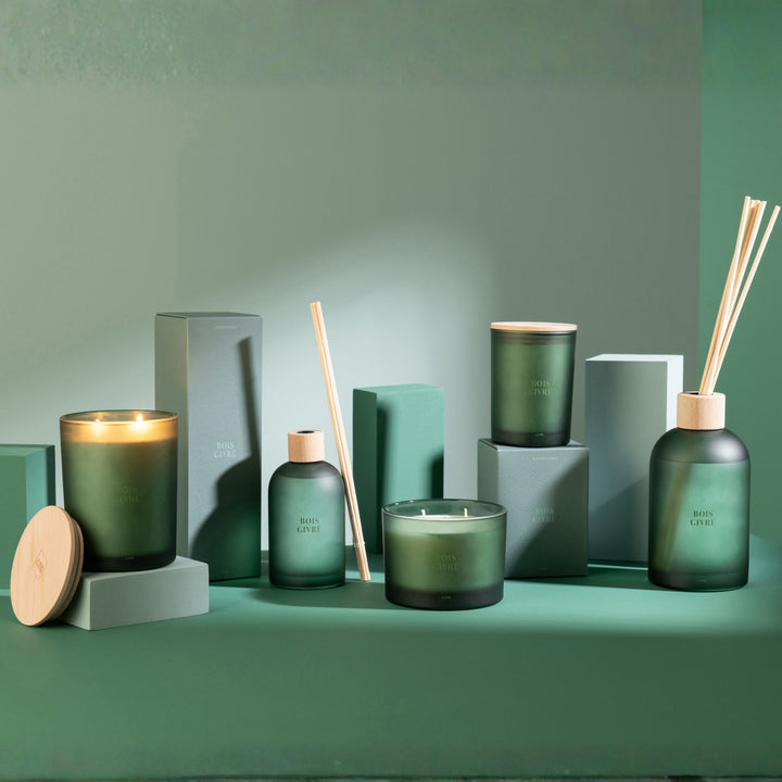 Lifestyle setup featuring the Bois Givré candle collection arranged on green-toned blocks.