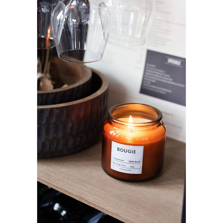 Bougie Small Candle displayed near glassware on a wooden shelf.
