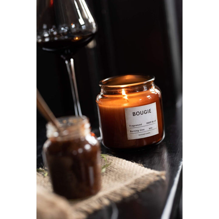 Bougie Small Candle displayed near glassware on a wooden shelf.