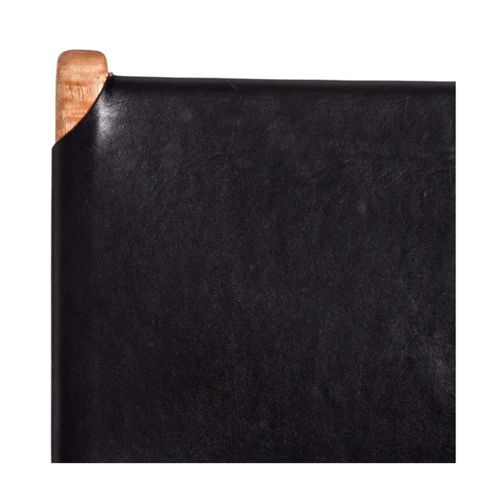 Close-up of smooth black leather backrest texture on teak structure.