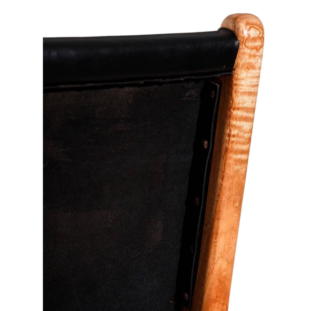 Detail of black leather backrest with visible stitching and teak wood frame.