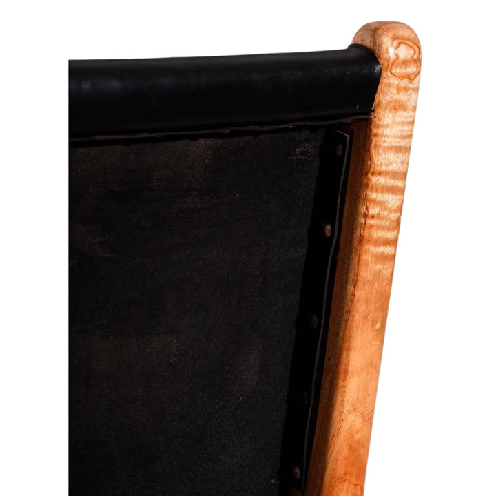 Detail of black leather backrest with visible stitching and teak wood frame.