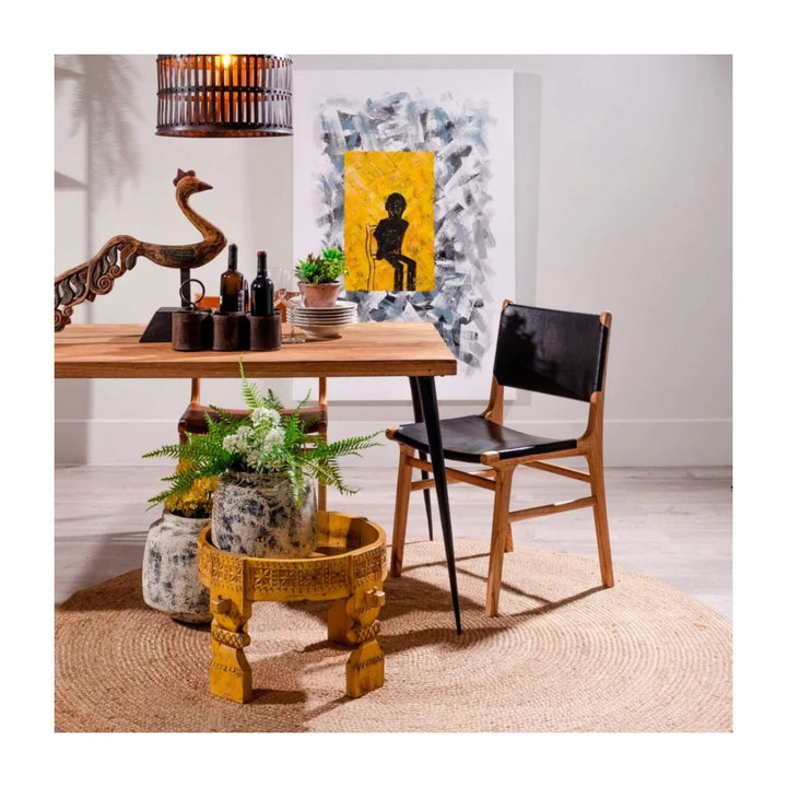 Buffalo teak and leather dining chair styled at a wooden dining table in a natural interior setting.