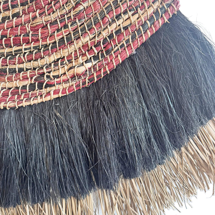 Close-up of Bayu Wall Deco, handwoven from abaca, cotton, and rattan with natural and black fringe in earthy tones.