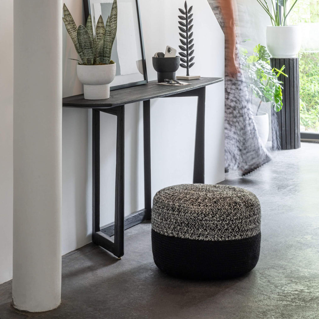 Black acacia console styled in a modern entryway with decor.
