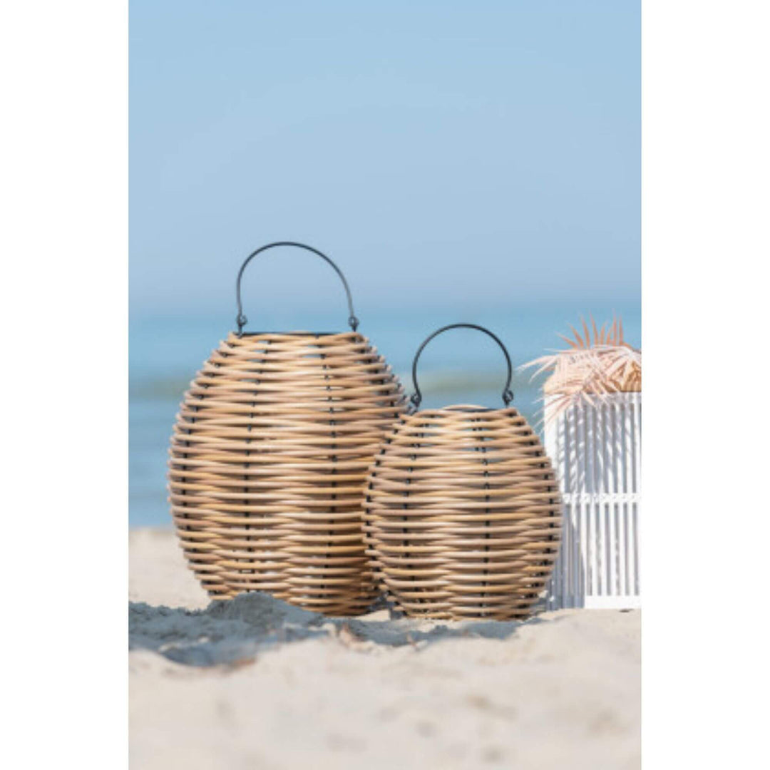 Cane lantern with LED candle styled outdoors on sand showing natural woven design