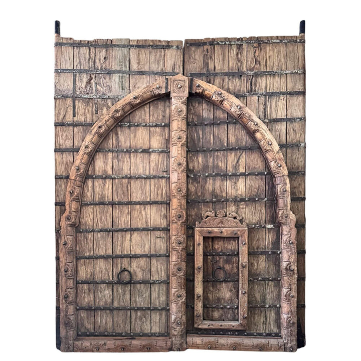 Front view of the Castle Door in sheesham wood with monumental double panels, carved arch detailing, and dark metal straps