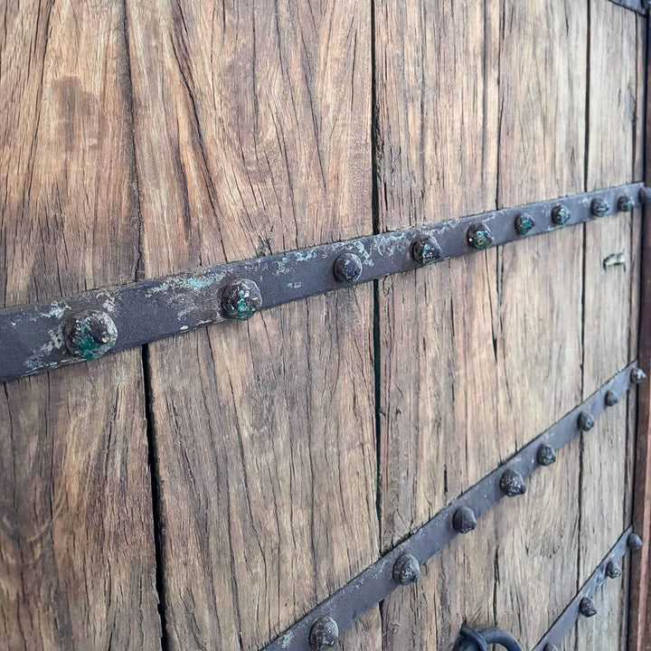 Close-up of the Castle Door showing dark metal straps and rows of decorative studs across the wood panels